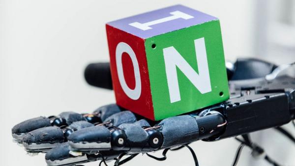 Ρομποτικό χέρι παίζει στα δάχτυλα έναν κύβο