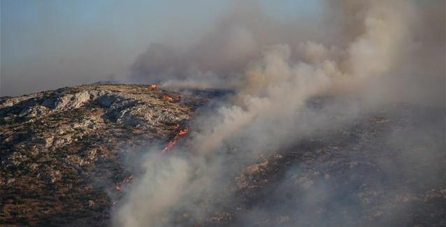 Ενας εποχικός πυροσβέστης επιχειρεί κατάσβεση πυρκαγιάς στην Ιο