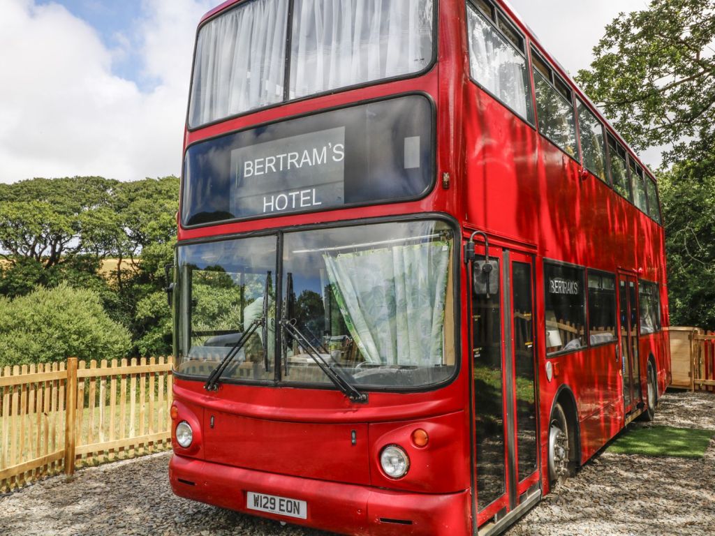 Ρετρό διώροφο λονδρέζικο λεωφορείο περιμένει σε ένα λιβάδι να σας φιλοξενήσει