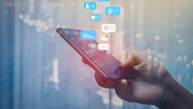 εικόνα που δείχνει χρήστρια social media να πληκτρολογεί στο κινητό, ενώ προβάλλουν «σύννεφα» με ενημερώσεις