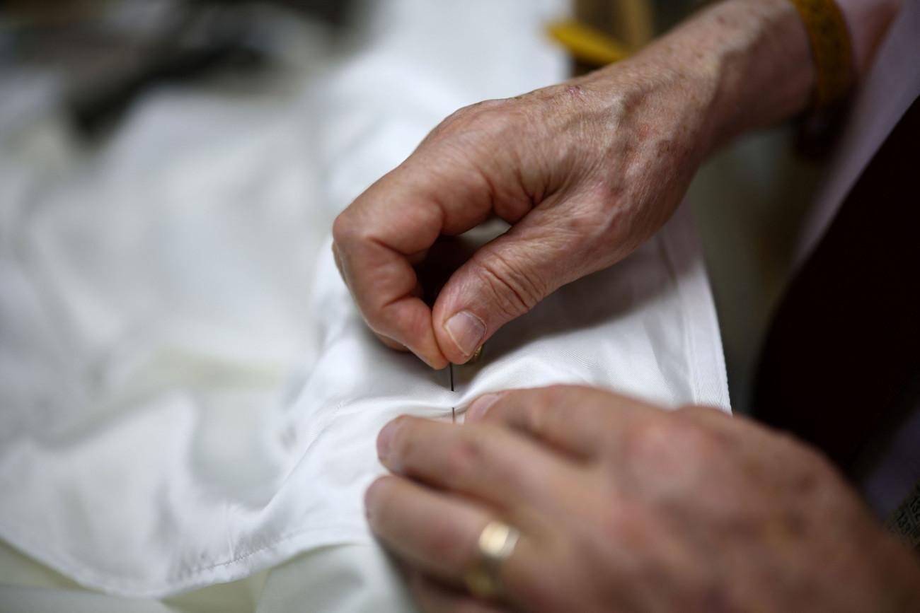 εικόνα που δείχνει τον Ρανιέρι Μαντσινέλι να ράφει λευκό παπικό ράσο