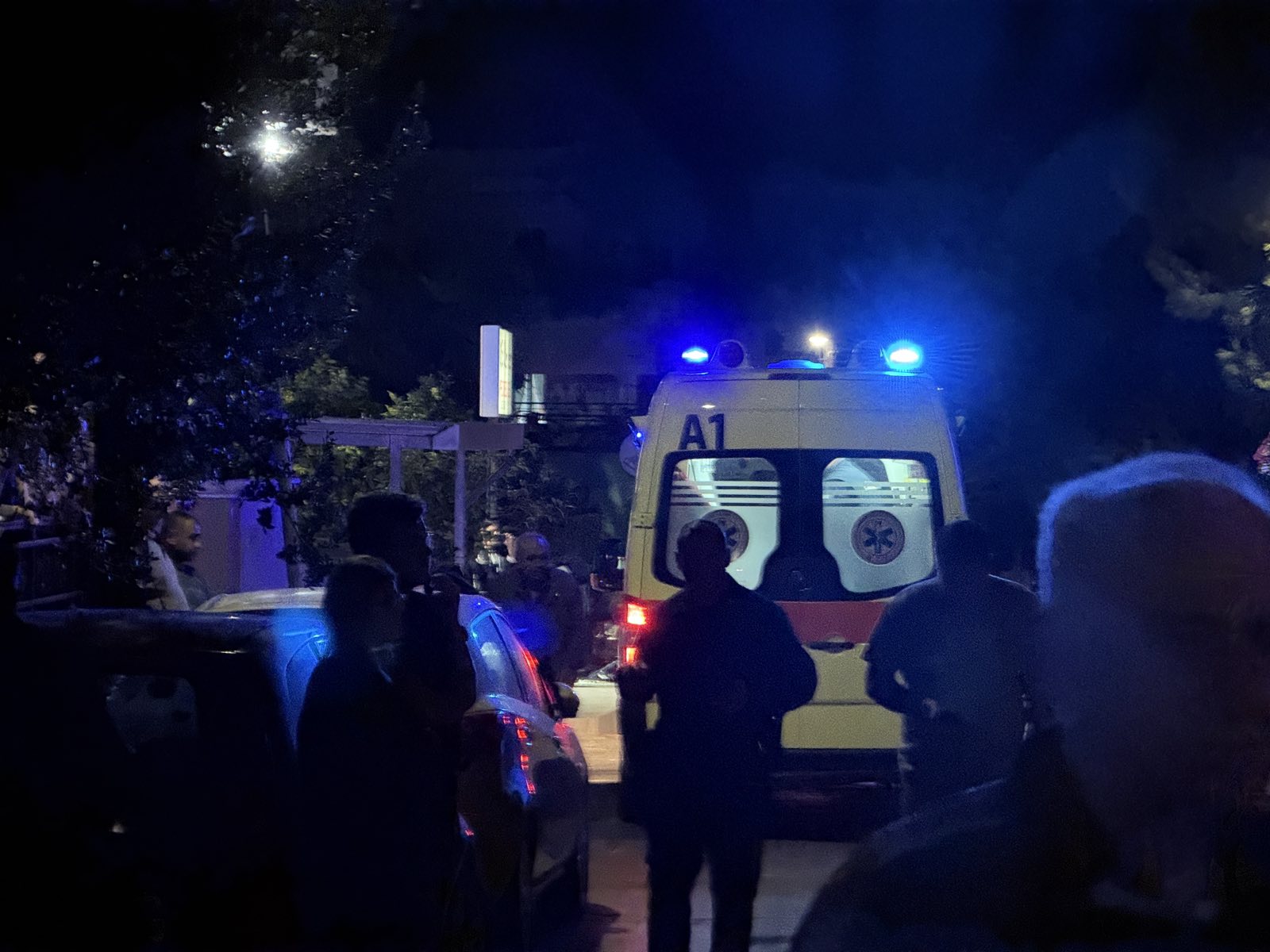 εικόνα που δείχνει κατοίκους έξω από το σπίτι στο Ηράκλειο, ενώ ασθενοφόρο του ΕΚΑΒ έχει παραλάβει τον 60χρονο για να τον μεταφέρει στο ΠΑΓΝΗ