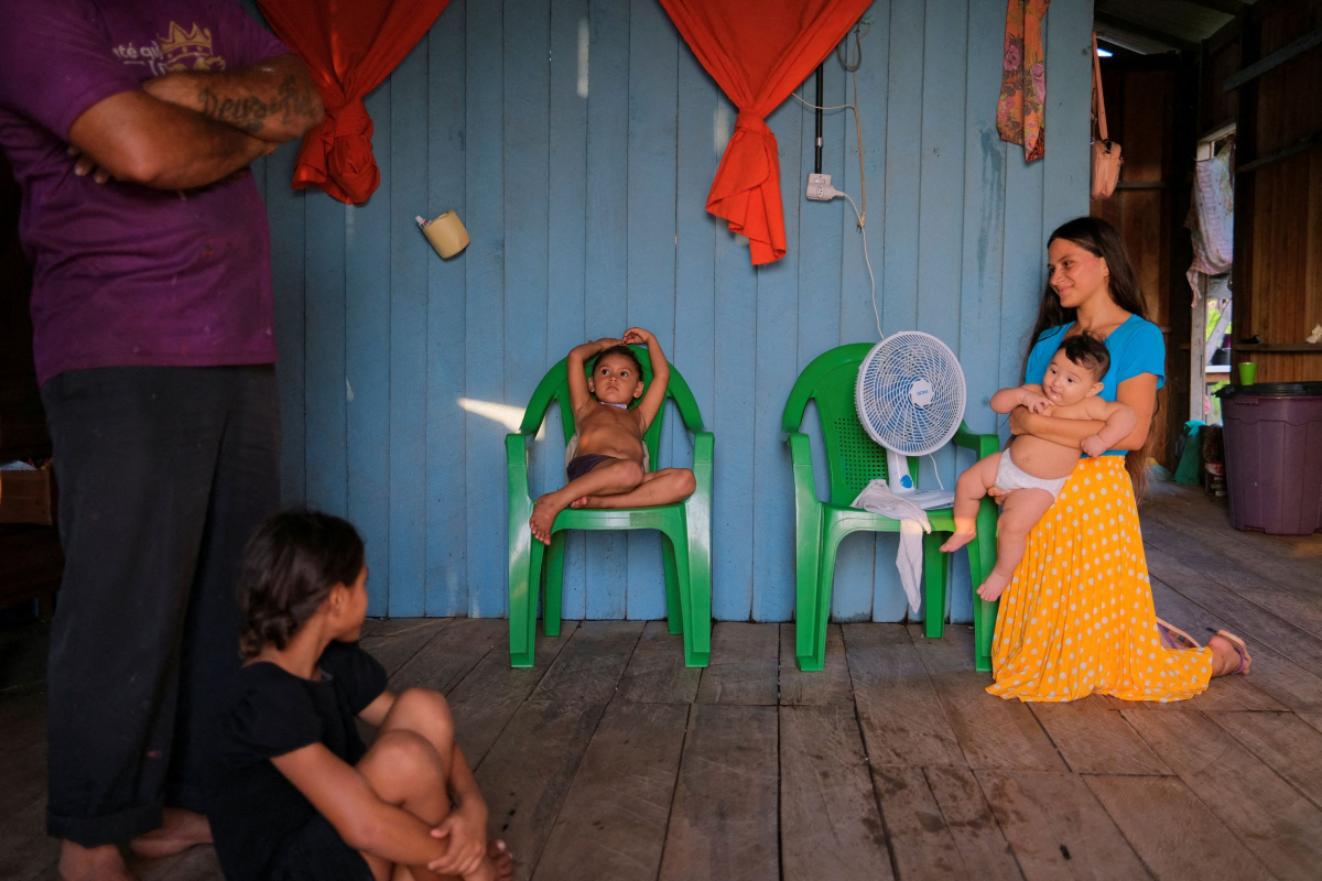 Η οικογένεια της Νιουμπιάν Φερέιρα Σάργες δροσίζεται με έναν ανεμιστήρια που λειτουργεί με φωτοβολταϊκά στη στέγη στο Μπρέβες της Βραζιλίας στις 28 Νοεμβρίου 2025 (Reuters)