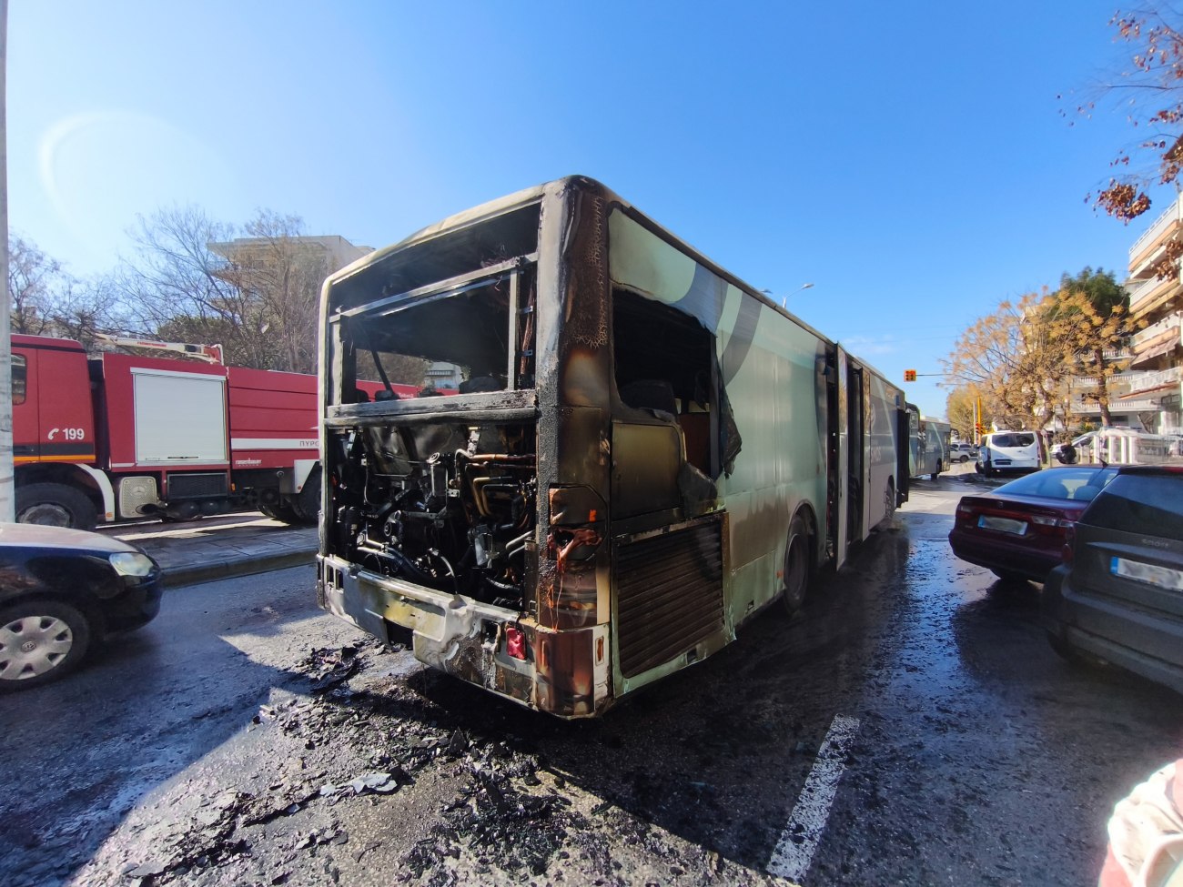 εικόνα που δείχνει το καμμένο λεωφορείο στη Θεσσαλονίκη, με το πυροσβεστικό όχημα να διακρίνεται στο βάθος