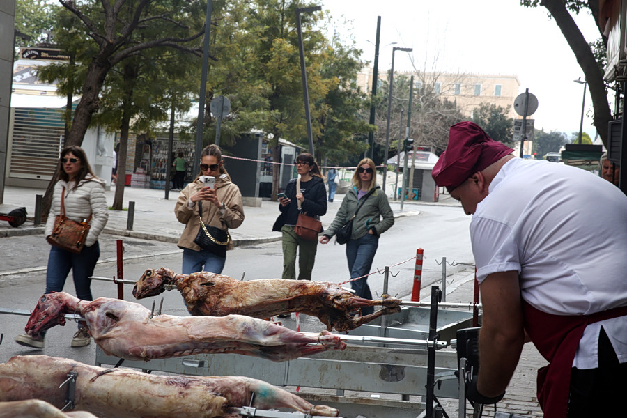 εικόνα που δείχνει τουρίστριες να φωτογραφίζουν τα αρνιά που ψήνονται στην οδό Μητροπόλεως, στο Σύνταγμα