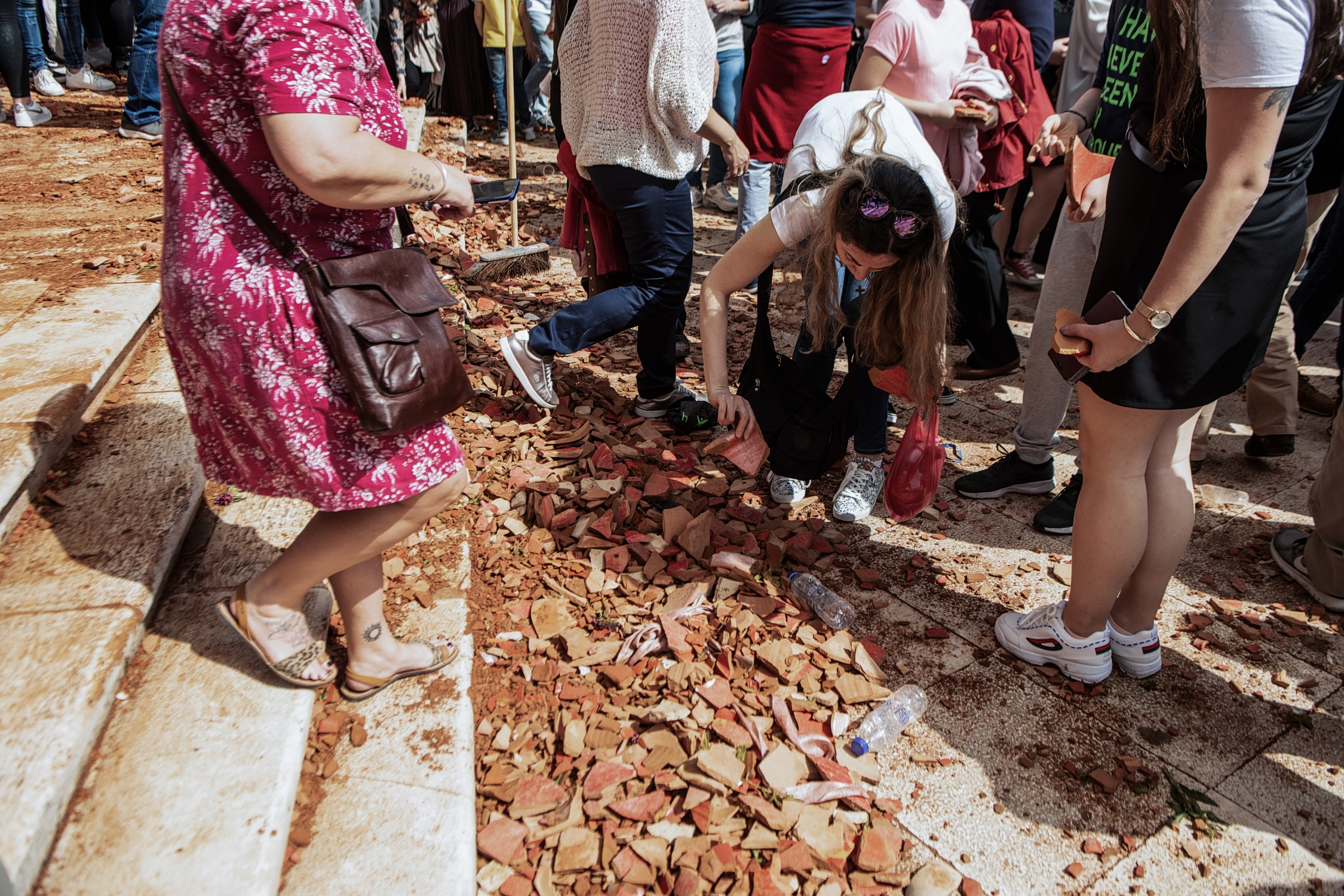 εικόνα που δείχνει μια κοπέλα να σηκώνει κομμάτι από του σπασμένους μπότηδες, που σύμφωνα με την παράδοση θεωρείται «καλή τύχη»