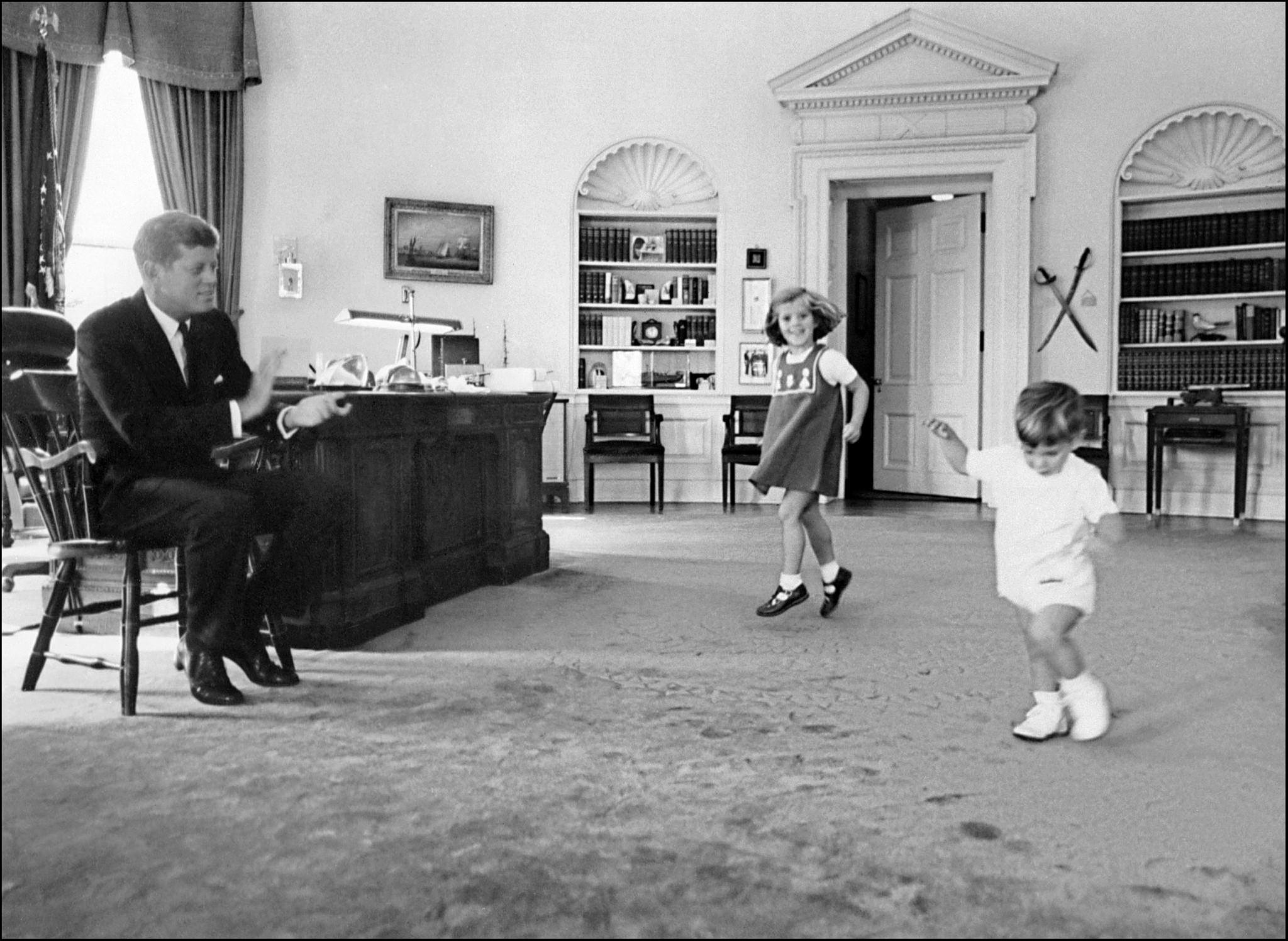 Φωτογραφία της 25ης Νοεμβρίου 1962 που δείχνει τον Τζον Φ. Κένεντι Τζούνιορ (δεξιά) να χορεύει με την αδελφή του Καρολάιν, ενώ ο πατέρας τους, ο αείμνηστος Πρόεδρος των ΗΠΑ Τζον Φ. Κένεντι, χειροκροτεί στο Οβάλ Γραφείο του Λευκού Οίκου στην Ουάσινγκτον. EPA PHOTO/AFP-FILES