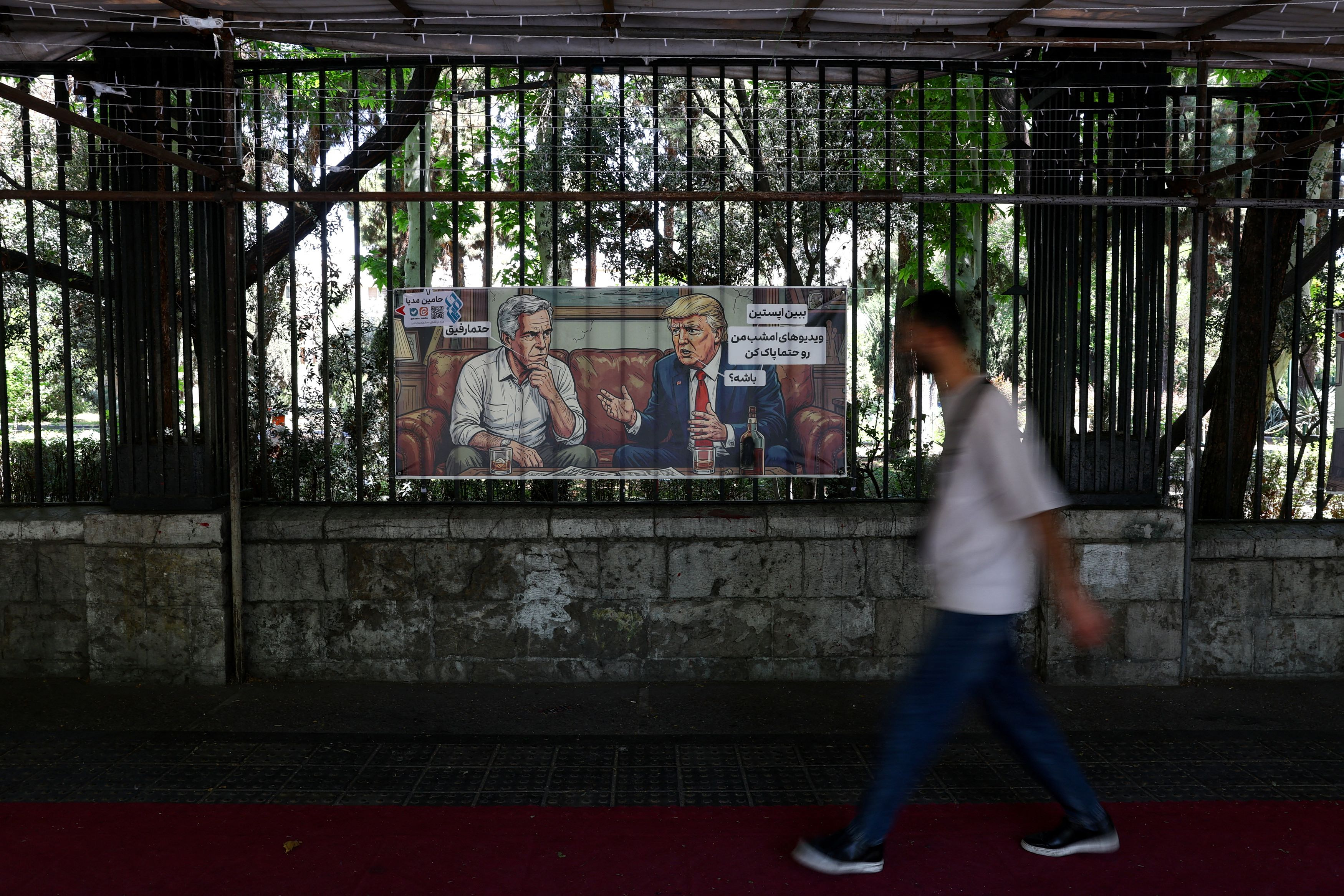 Ένας άνδρας περπατά μπροστά από εικόνα που απεικονίζει τον πρόεδρο των ΗΠΑ Ντόναλντ Τραμπ και τον εκλιπόντα χρηματιστή και καταδικασμένο για σεξουαλικά αδικήματα Τζέφρι Έπσταϊν, σε δρόμο στην Τεχεράνη του Ιράν, στις 12 Μαΐου 2026. Majid Asgaripour/WANA (West Asia News Agency) μέσω REUTERS.