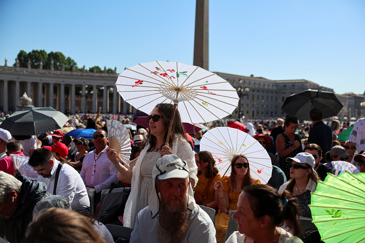 Πιστοί προστατεύονται με παρασόλ περιμένοντας να ακούσουν τον πάπα Λέοντα στην πλατεία του Αγίου Πέτρου στις 27 Μαΐου 2027 (Reuters)