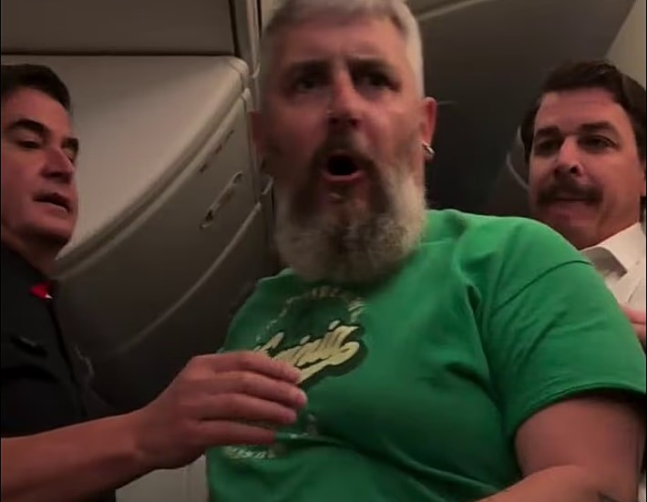 Εικόνα που δείχνει μέλη του πληρώματος της Qantas να προσπαθούν να ηρεμήσουν το μαινόμενο επιβάτη