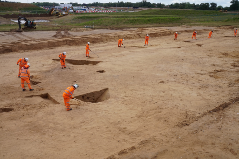 Αρχαιολόγοι πεδίου της Oxford Cotswold Archaeology ανασκάπτουν τον νεολιθικό επιμήκη περίβολο, χρησιμοποιώντας εργαλεία όπως φτυάρια, καρότσια μεταφοράς και τσάπες.Πηγή φωτογραφίας: Oxford Cotswold Archaeology.